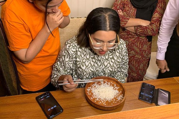 Woman uses chopsticks to eat one grain of rice at a time Woman uses chopsticks to eat one grain of rice at a time
